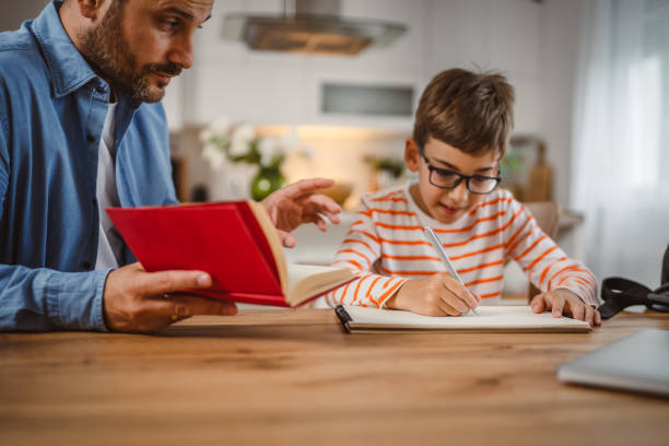 istock Father with book assistance and help son to do homework together home 2155426522