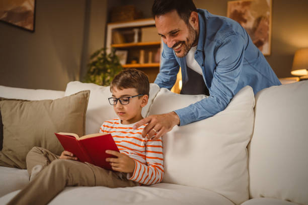 istock Father look at his son how read a book and spend time together at home 2155432221