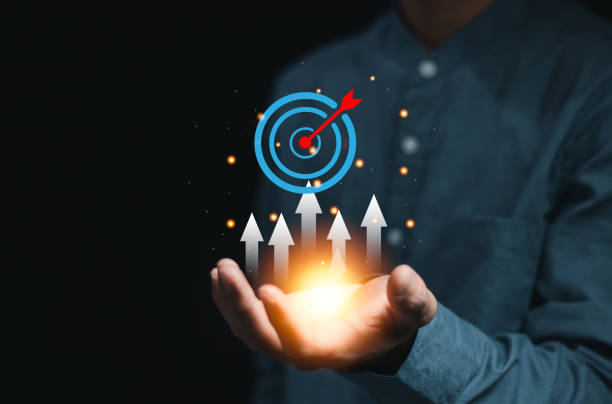 istock Businessman holding target icon with up arrow on virtual screen. Business objective and targeting business concept. Strategic planning for business growth and target customer group. 2155433507