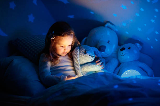 istock Little girl reading a book in bed 2155434319