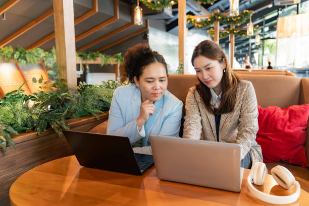 istock Two cheerful female coworkers, focussing on thier projects and diligently working on their laptops at a café to foster a relaxed atmosphere conducive to creativity, reflecting their professionalism. 2155438921