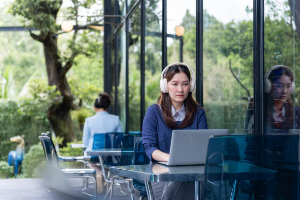 Amidst the cozy charm of the café, a Asian female in casual attire exuding tranquility as she concentrating on her laptop tasks. This scene eloquently illustrating the effortless balance between her professional obligations. en medio del acogedor encanto de la cafetería, una mujer asiática con atuendo informal exuda tranquilidad mientras se concentra en las tareas de su computadora portátil. esta escena ilustra elocuentemente el equilibrio sin esfuerzo entre sus obligacione
