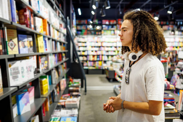 istock Young boy examines new books in bookstore 2155441019