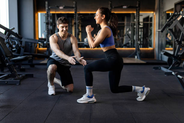 istock Personal trainer controlling and showing sportswoman how to do lunges correctly while kneeling in gym, side view 2155448017