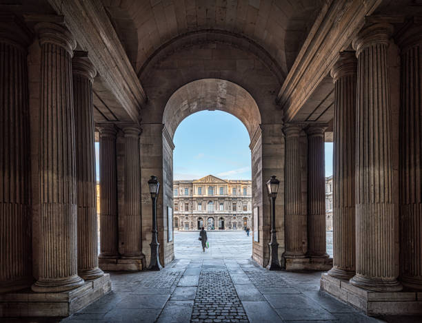 Archway to the Louvre courtyards October 19, 2021 - Paris, France: People walking through the Archway to the Louvre courtyards. Louvre Museum outside during day time, is one of the world's largest museums in Paris building pillars and lights at the louvre paris france stock pictures, royalty-free photos & images