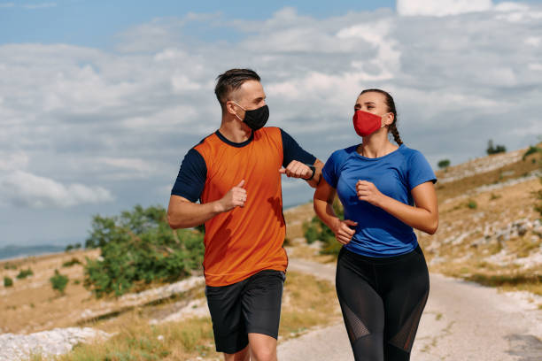 istock Couple running in nature at morning wearing protective face masks 2155451996