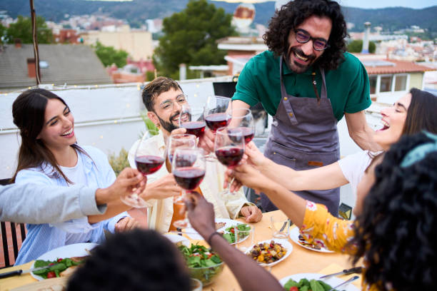istock Joyful millennial group friends toasting glasses red wine celebrating rooftop barbeque summer party. 2155455580
