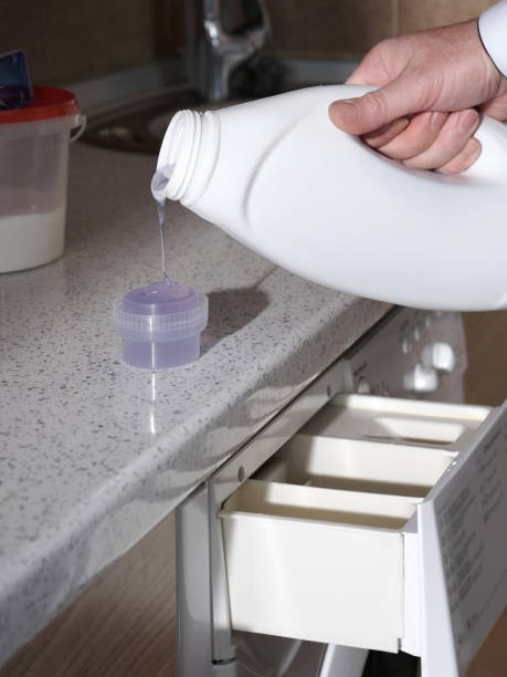 istock Close-up a man pours liquid washing gel into the container for a washing machine. 2155462642