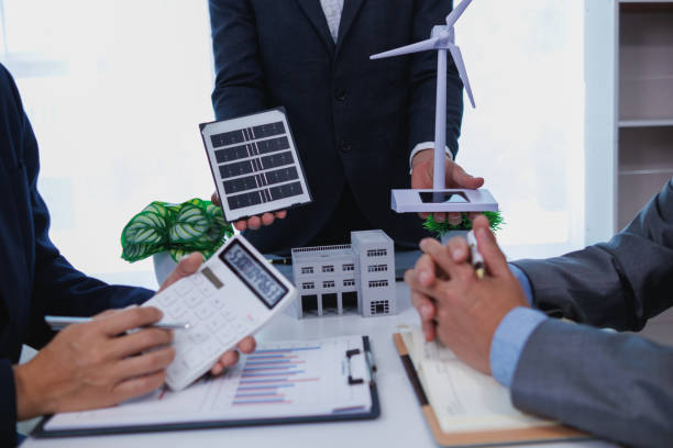 istock Businessmen, investors and electrical engineers discuss clean energy residential projects help reduce global warming and use clean energy from wind and sunlight. concept clean energy projects 2155463750