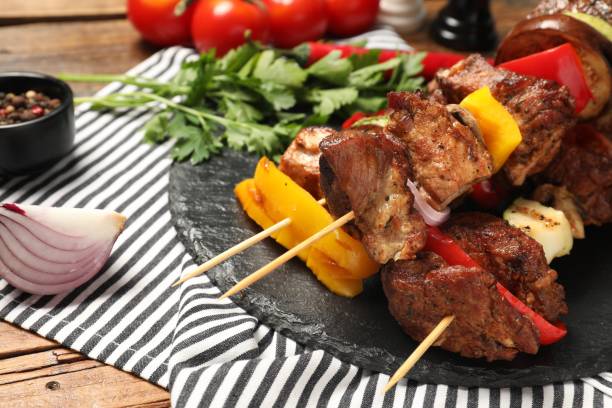 istock Delicious shish kebabs with vegetables on wooden table, closeup 2155473361