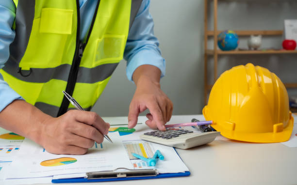 A foreman sits at a desk in an office, Calculating costs, Planning construction, Calculating structures, Planning and calculating project construction costs, Project presentation plan. A foreman sits at a desk in an office, Calculating costs, Planning construction, Calculating structures, Planning and calculating project construction costs, Project presentation plan. Contractor’s managment .