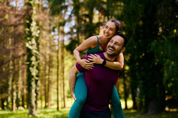Happy athletic couple piggybacking in the park.