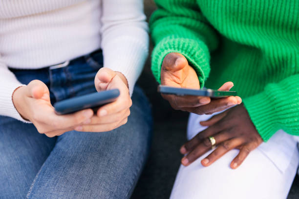 hands of two women using mobile phone