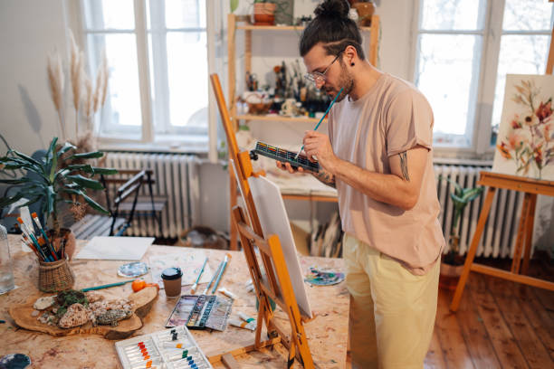 istock Talented hipster artist painting on easel at creative art studio. 2155479136
