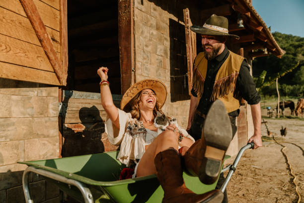 istock Young happy farmer couple having fun with wheelbarrow at ranch. 2155479144
