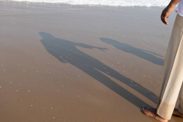 Golden hour on the sandy beach: A mother and daughter hold hands, creating a serene silhouette against the ocean backdrop.