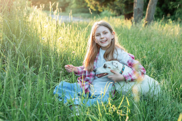 A child with a dog in nature, girl playing with a dog on green grass