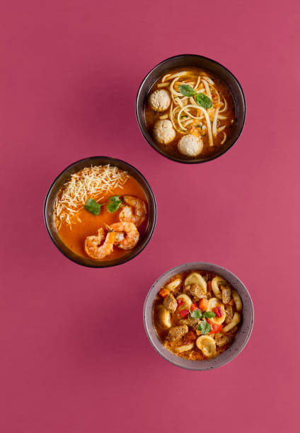 Three Bowls of Delicious Asian Soup with Shrimp, Meatballs, and Vegetables on Red Background â Top View