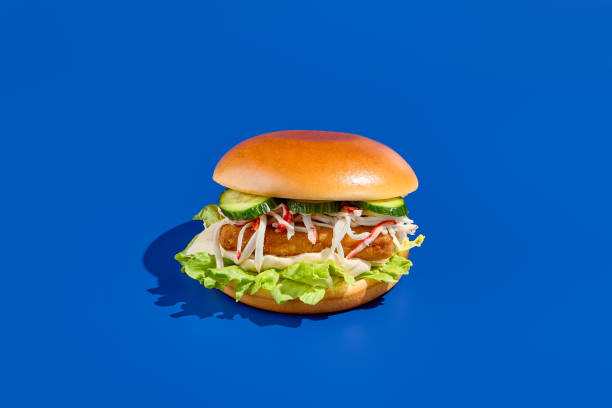 istock Appetizing fish burger on blue background, fish patty, fresh greens, minimalist style, modern food photography, ideal for takeout, horizontal composition, succulent fish fillet, healthy alternative 2155482197