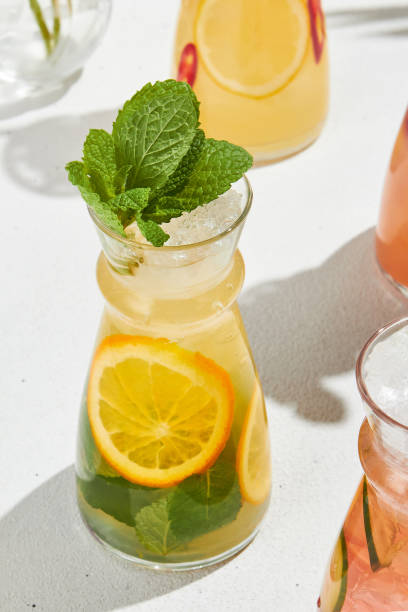 istock Summer citrus lemonade with mint in jar. Orange and mint lemonade on white background with shadows. Fresh summer drink in minimal style. Aesthetic lemonade in transparent pitcher. 2155482254