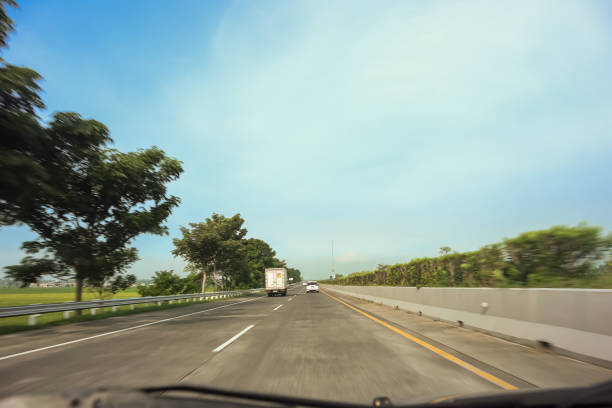 Empty highway traffic with asphalt road and green trees around