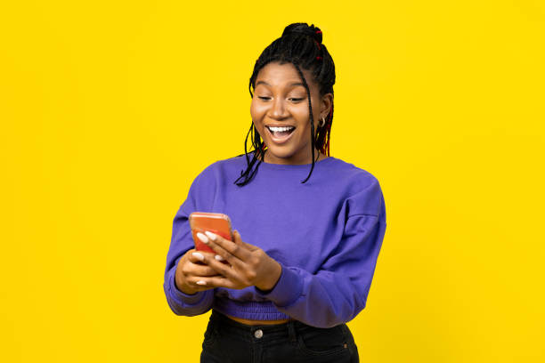 istock Woman using smartphone on a vibrant yellow background. 2155483647
