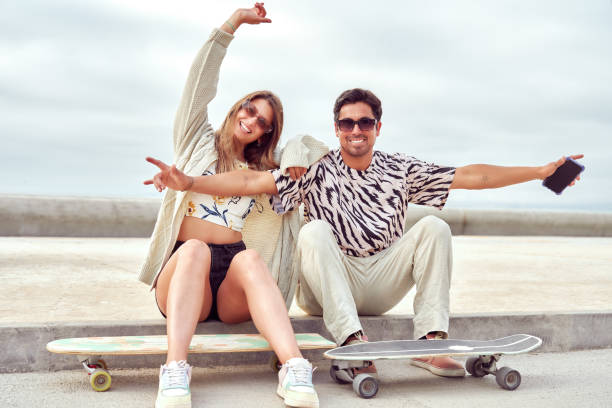 istock heterosexual couple sitting on sidewalk with skateboards hanging out and having fun 2155484041