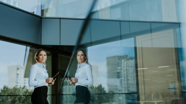 istock Confident businesswoman holding digital tablet while standing outside modern office building at noon 2155484858