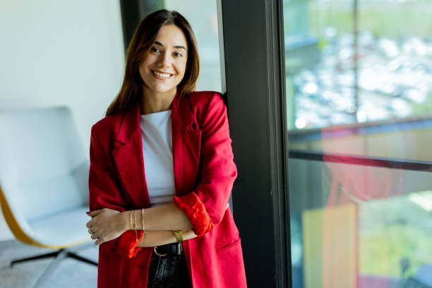 istock Confident young professional in red blazer smiling at modern office environment 2155484979