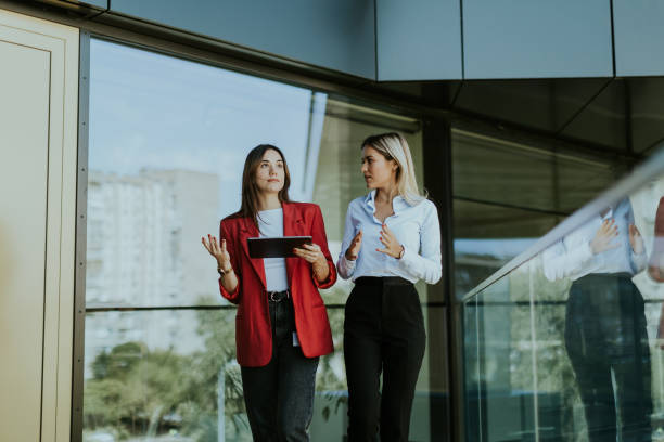 istock Two businesswomen discuss strategy outside modern office building in daylight 2155484983