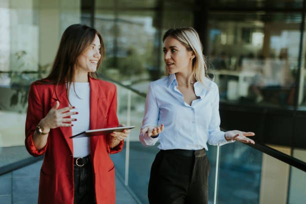 istock Two businesswomen discuss strategy outside modern office building in daylight 2155485039