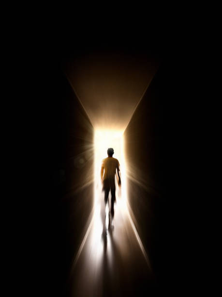 istock Single man walking at dark narrow corridor in to glowing light 2155485141