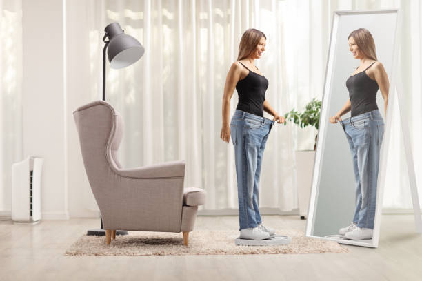 istock Young woman on a scale in front of a mirror 2155485412