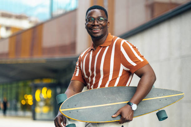 istock Smiling man carrying his longboard and walking 2155485564