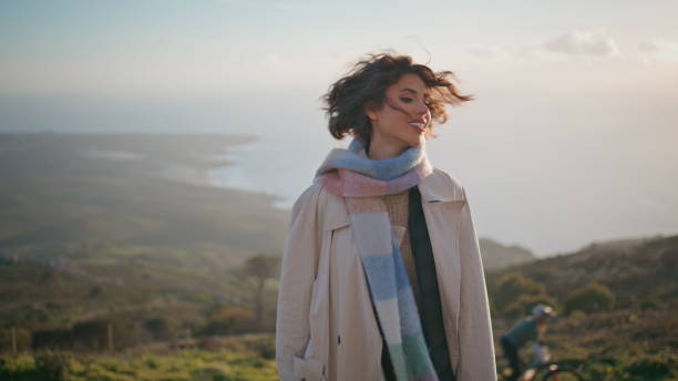 Elegant traveler standing scenic coastal twilight blown by cool wind closeup.