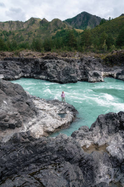Woman at the river Katun at summer day. Trip on Altai Mountains in Altai Republic
