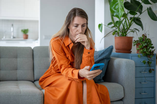 istock Stressed woman looks at smartphone screen nervously pressing palm to lips, reading unpleasant news. 2155487864