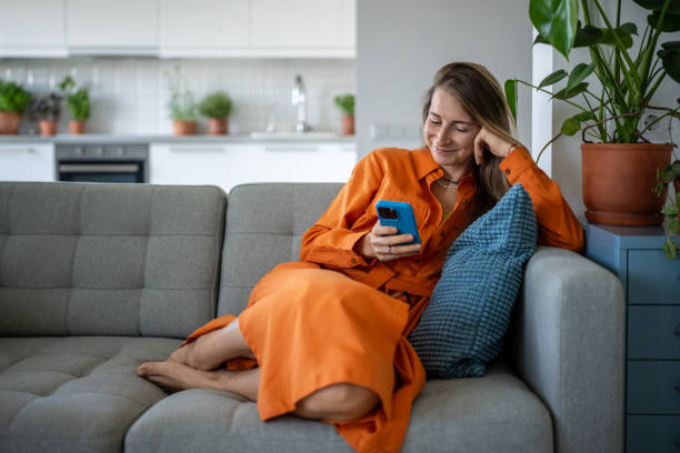 istock Happy woman using cellphone at home sofa. Pleased relaxed female have internet fun, chatting online. 2155487914