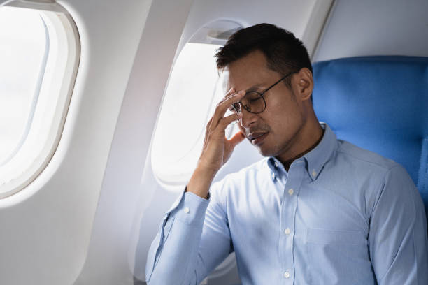 istock Tired asian man with headache feeling sick while sitting in the airplane , Passengers near the window. 2155488463