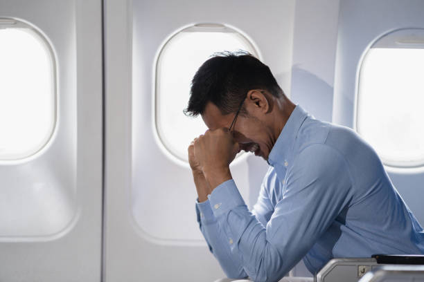 istock Tired asian man with headache feeling sick while sitting in the airplane , Passengers near the window. 2155488464