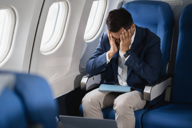 istock Tired asian man with headache feeling sick while sitting in the airplane , Passengers near the window. 2155488465