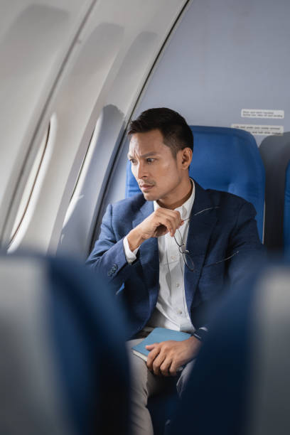 istock Tired asian man with headache feeling sick while sitting in the airplane , Passengers near the window. 2155488478