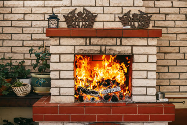 istock A cozy fireplace set in a light brick wall, with bright orange and yellow flames roaring as they consume several dark logs 2155489111