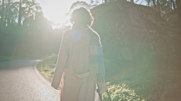 istock Silhouette woman walking forest road at dawn backlit by morning sunlight. 2155489804
