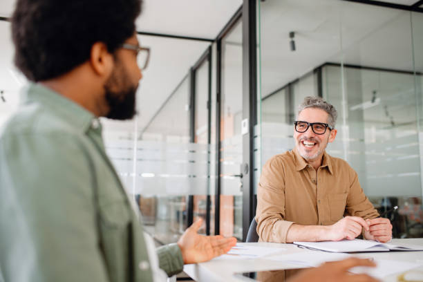 istock Two male professional colleagues are engaged in a friendly discussion at the office 2155493354
