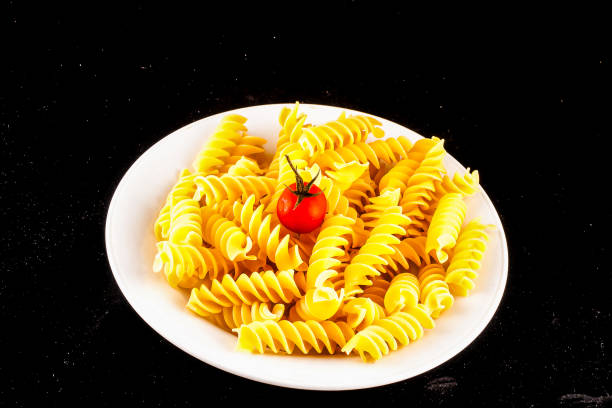 A plate of pasta with a tomato on top, image