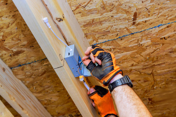 Electrician installing recessed ceiling lights with power junction box in a new home