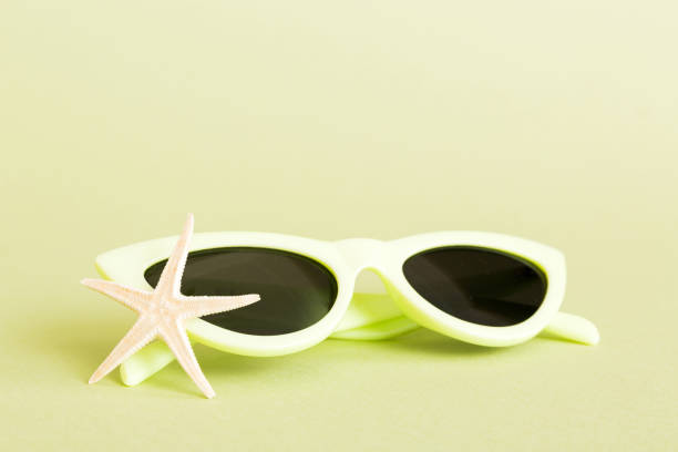 sunglasses with seashell lying on table background. Sunglasses on summer background. Top view flat lay with copy space for text.