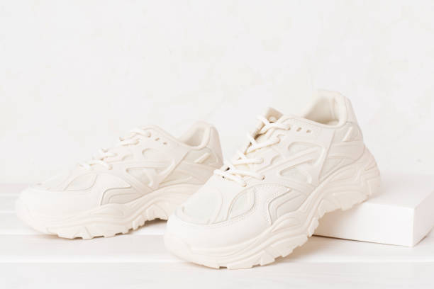 istock White woman trendy sneakers on concrete background 2155497253