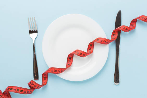 istock Measuring tape with empty plate on wooden background, top, view. Weight loss concept 2155497294